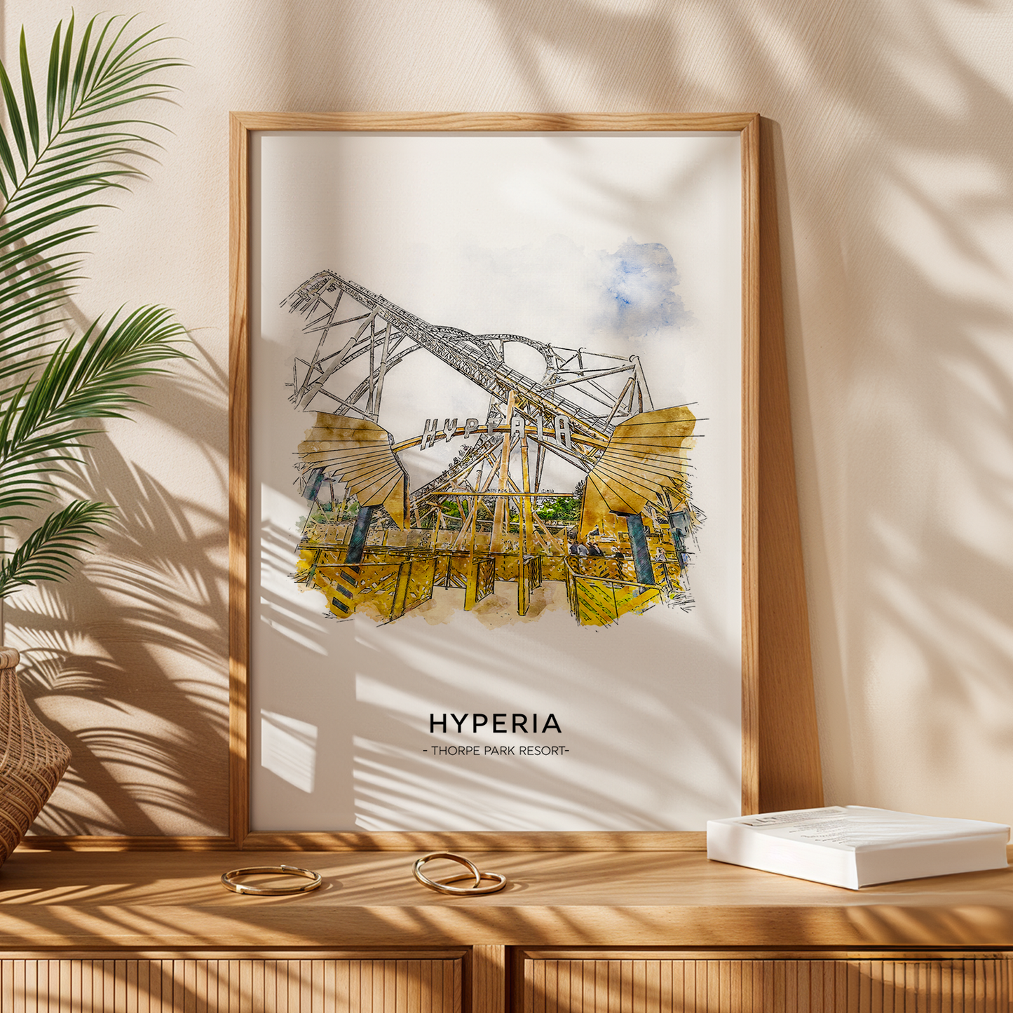 Framed artwork titled 'Hyperia' on a wooden surface with a plant and box in the background.
