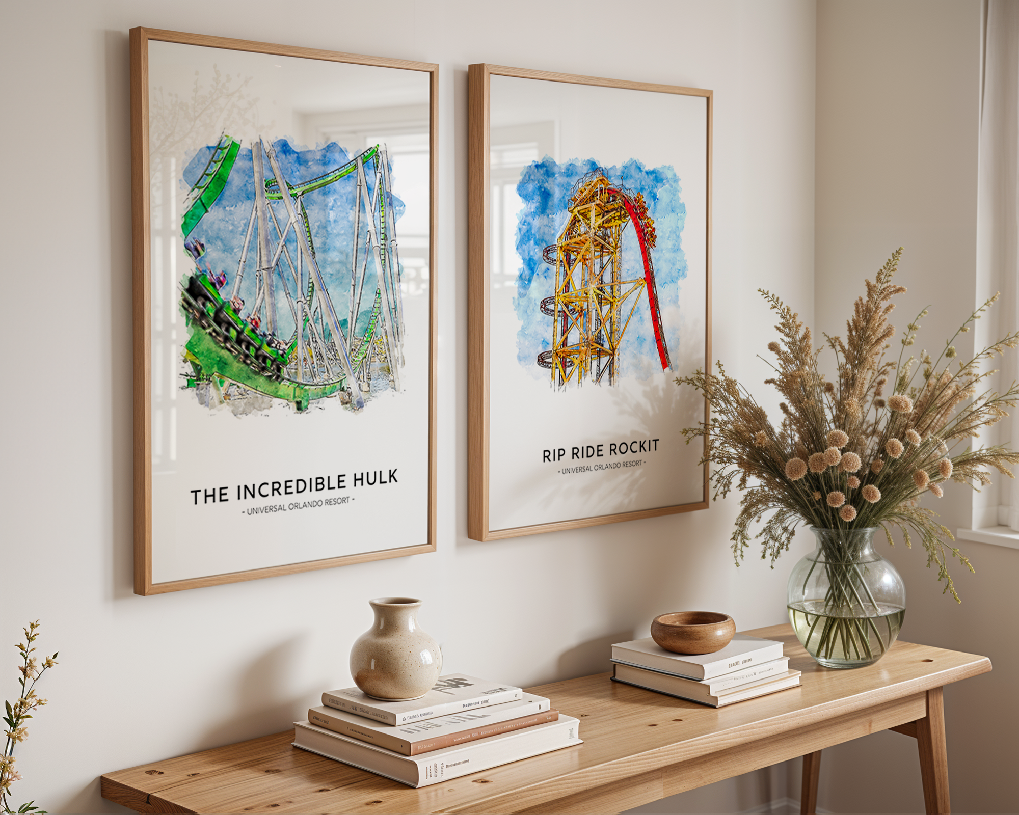 Two framed artworks of roller coasters on a wall above a wooden console table with decorative items.