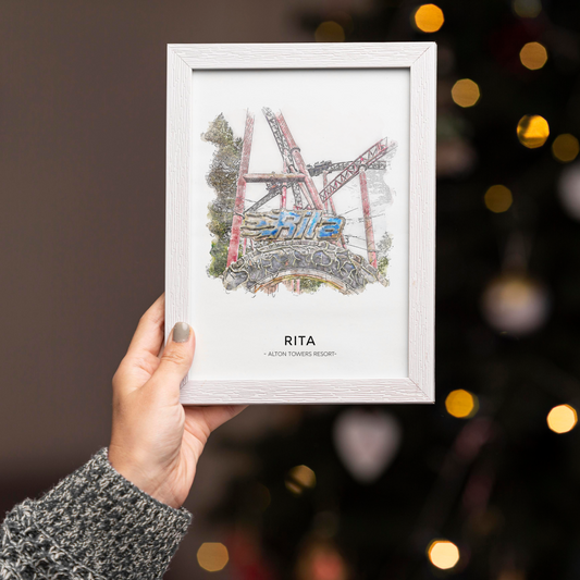 Framed artwork of the Rita rollercoaster in a white frame held in front of a blurred festive background.